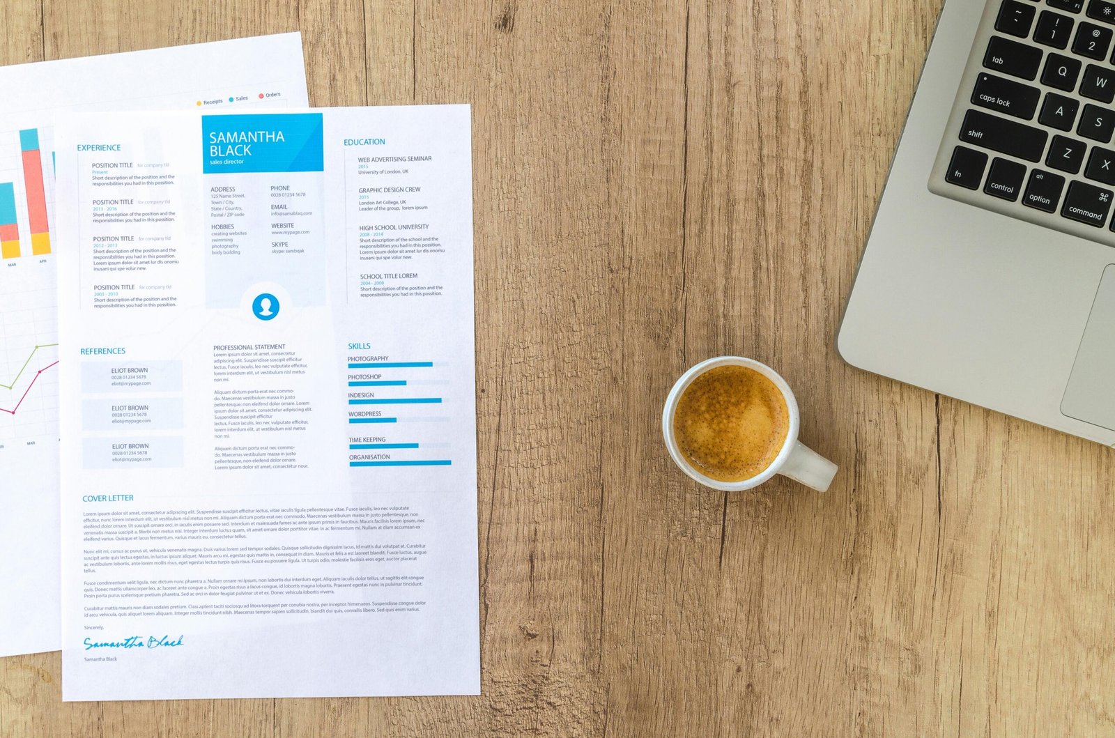 Documentos impresos con gráficas junto a una laptop y un café